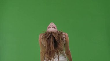 A woman dressed as a dead bride, in a white wedding dress, moves terribly like a zombie. The ghostly bride stands against a green chroma key backdrop for Halloween or spooky projects.
