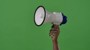 A creepy zombie hand holds a loudspeaker, covered in dirt and decaying skin, isolated on a green chroma key background. Perfect for Halloween party graphics, spooky decorations, and festive media design.
