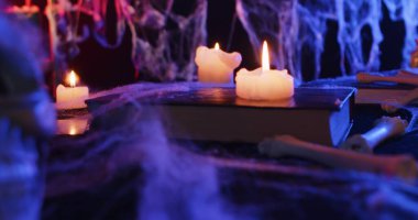 A Halloween setting featuring candles, spider webs, and eerie lighting, creating a haunting atmosphere.