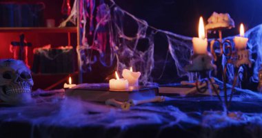 Spooky Halloween scene with lit candles, a skull, and spider webs creating a mysterious atmosphere.