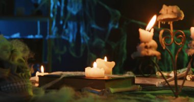 Spooky Halloween scene with lit candles, a skull, and spider webs creating a mysterious atmosphere.