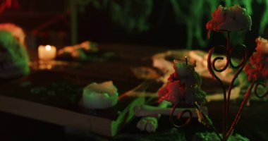 Erimiş mumlar, örümcek ağları ve ürkütücü bir atmosfer yaratan eski bir kitapla donuk bir Cadılar Bayramı sofrası..