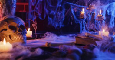 Eerie Halloween scene with a skull, candles, and cobwebs creating a spooky, atmospheric setting.