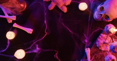 Kafatası, kemikler ve mor ışıklı mumların ve örümcek ağlarının olduğu ürkütücü Cadılar Bayramı sahnesi. Üst çekim.