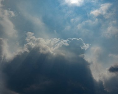 Koyu gri fırtına bulutlarının yer aldığı güçlü ve dramatik bir bulut. Parlak güneş ışınlarının parlak mavi gökyüzünü aydınlattığı bir yer. Bu dinamik görüntü saf güzelliği ve değişen havayı yakalar..