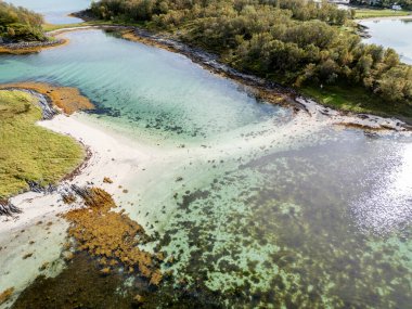 Bu nefes kesici hava fotoğrafıyla uzak bir sahil cennetinin el değmemiş güzelliğini keşfedin. Kristal berraklığında turkuaz sular, kumlu deniz tabanının ve canlı yeşil ve kahverengi yosun yataklarının karmaşık desenlerini ortaya çıkarır..