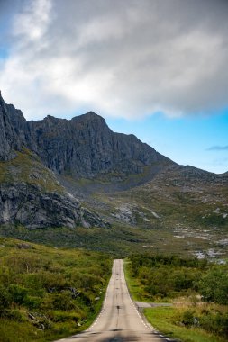 Uzak bir dağ yolunun büyüleyici görüntüsüyle destansı, engebeli tepelere doğru sonsuz bir yolculuğa çıkın. Geniş ve el değmemiş vahşi doğayla çevrili. Dinamik bir gökyüzü altında hem güneş hem de bulutlarla..