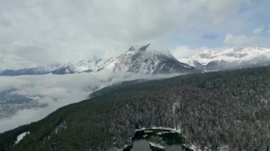 Görkemli bir kış dağ manzarası sersemletici hava manzarası, karla kaplı tepeler, dingin bir orman ve donmuş bir göl.