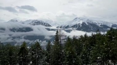 Serene Winter Landscape: Kısmen donmuş bir göl üzerinde insansız hava aracı uçuşu ve aşağıdaki resimli köylü karla kaplı dağlar