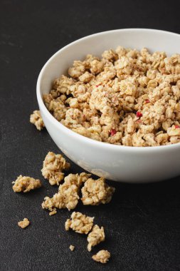 Siyah masada beyaz kasede granola. Siyah arka planda sağlıklı kahvaltı. Yan görünüm.