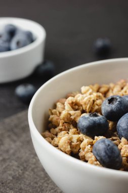 Siyah peçetede yaban mersinli granola. Siyah masada sağlıklı yiyecekler. Ev yapımı kahvaltının yan görüntüsü.