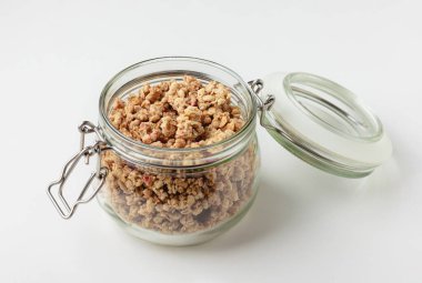 Kavanozda granola, ışık arka planda. Beyaz masada ev yapımı kahvaltı. Sağlıklı yiyeceklerin yan görünüşü.