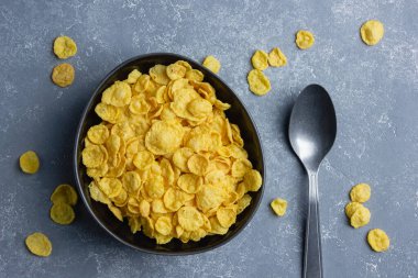 Mavi arka planda siyah kasede mısır gevreği.