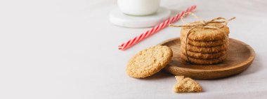 Oatmeal cookies are tied with craft thread on a wooden plate. Healthy food for breakfast or a snack with milk. Side view. Copy space.