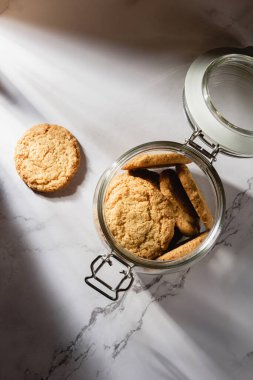 Mermer bir masada kavanozdaki yulaflı kurabiyeler. Kahvaltı ya da atıştırmalık sağlıklı yiyecekler. Üst görünüm.