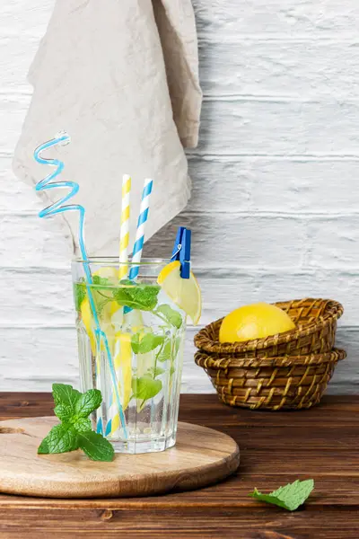 Bardakta naneli su, ahşap masada sepetin içinde limon. Taze narenciye manzarası.