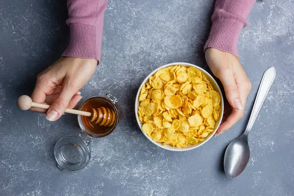 stock image Corn flakes with honey in white bowl on blue background.