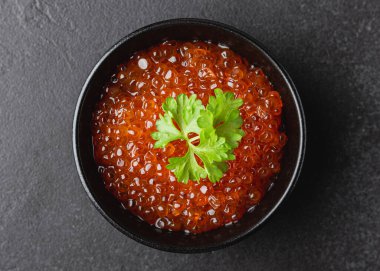 Maydanozlu somon havyarı. Karanlık bir arka planda deniz ürünleri atıştırması. Lüks yemekler. Üst görünüm.