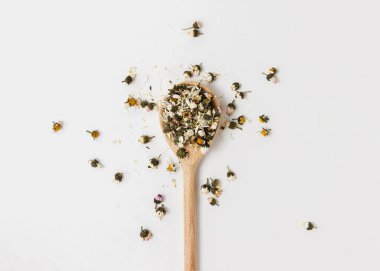 Beyaz arka planda tahta kaşıkta papatya çayı. Sağlıklı içeceğin en iyi görüntüsü.