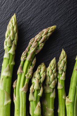 Green asparagus on a black background. Fresh and natural uncooked asparagus. Healthy plant food. Top view.