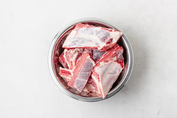 Kabın içinde çiğ biftek. Gri arkaplanda pişmemiş taze kırmızı et parçaları..