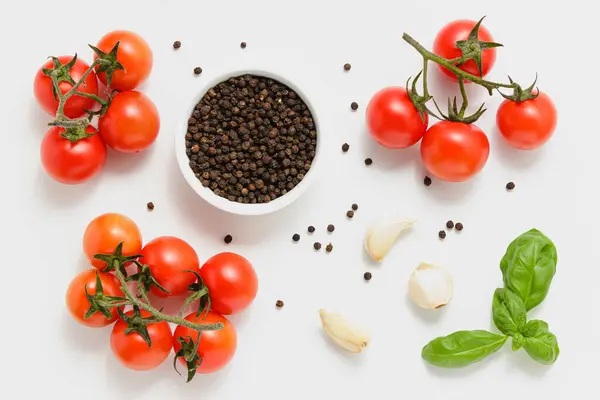Cherry tomatoes with basil, pepper and garlic. Fresh vegetables and herbs. Top view of healthy organic food on white background.