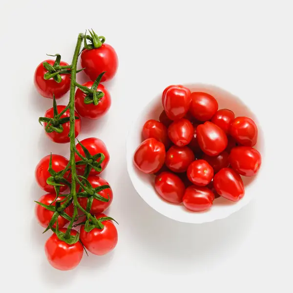 Kasede vişneli domatesler ve beyaz arka planda dallar. Taze sebzeler. Üst görünüm.