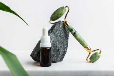 Beyaz mermer üzerinde yüz için yeşil taşlı masaj aleti. Moda bir kozmetik alet. Yaşlanma karşıtı terapi. Yan görüş. Düz yatıyordu. Boşluğu kopyala.