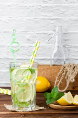 Naneli cam, limonlu limonlu şebeke torbası ve sandıklı tahta masa. Taze narenciye manzarası.