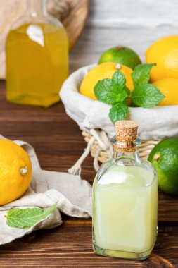 Limon ve limon şurupları cam şişede ve meyveler de arka planda. Taze narenciye ve el yapımı duş jeli veya sabun..