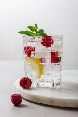 Mermerde buzlu ahududu kokteyli ve hafif arka plan. Nane ve limonlu ferahlatıcı bir meyve suyu..