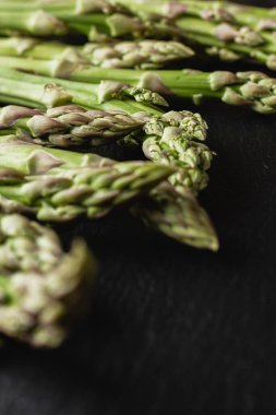 Green asparagus on a black background. Fresh and natural uncooked asparagus. Healthy plant food. Side view.
