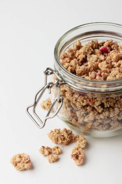 Kavanozda granola, ışık arka planda. Beyaz masada ev yapımı kahvaltı. Sağlıklı yiyeceklerin yan görünüşü.
