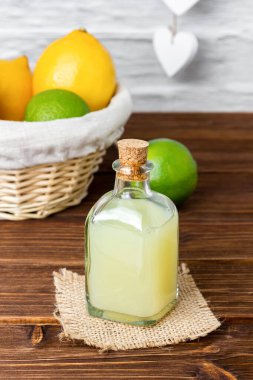 Cam şişelerdeki limon şurupları ve arka plandaki sepetteki limonlar. Taze narenciye manzarası.