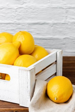 Tahta masada beyaz sandıkta limonlar. Taze narenciye manzarası.