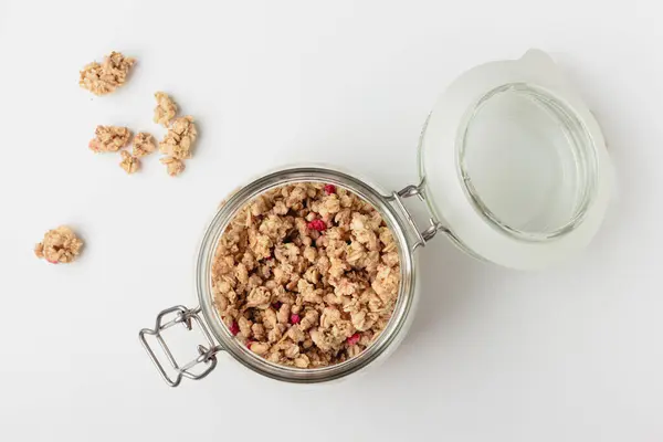 Kavanozda granola, ışık arka planda. Beyaz masada ev yapımı kahvaltı. Sağlıklı yiyeceklerin en üst görüntüsü.