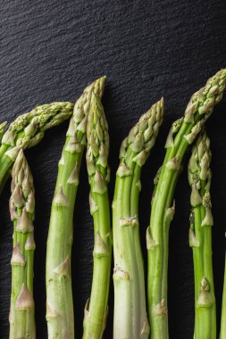 Siyah arka planda yeşil kuşkonmaz. Taze ve doğal pişmemiş kuşkonmaz. Yakın çekim. Sağlıklı bitkiler..