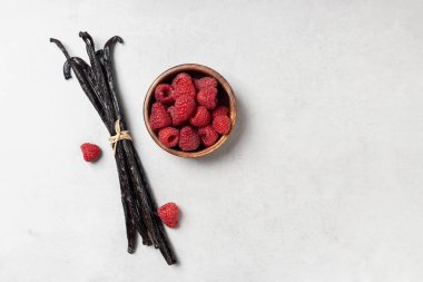 Fotokopi alanı olan gri arkaplanda ahududu olan vanilyalı fasulye. Kuru vanilya çubukları.