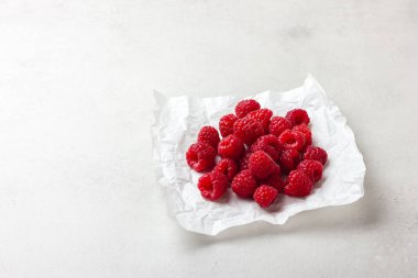 Beyaz arkaplanda beyaz bir kağıt üzerinde taze ahududu.