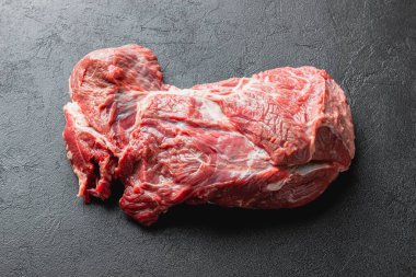 Siyah üzerine çiğ et. Koyu arkaplanda pişmemiş büyük bir parça kırmızı et..