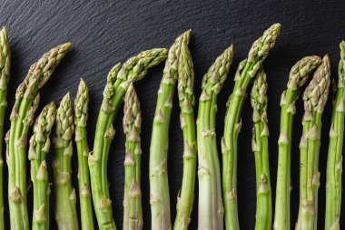 Siyah arka planda yeşil kuşkonmaz. Taze ve doğal pişmemiş kuşkonmaz. Yakın çekim. Sağlıklı bitkiler..