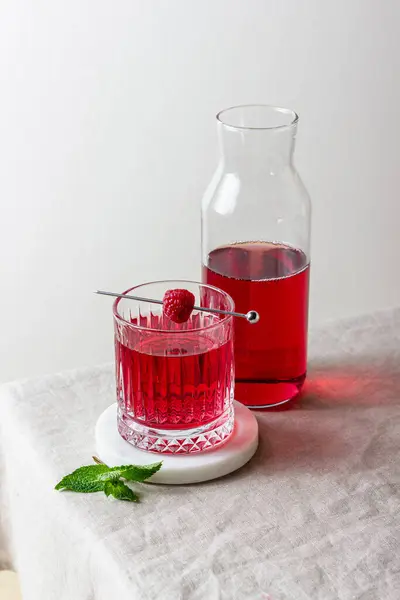 Mermer tezgahta bir bardakta ahududu kokteyli ve arka planda taze nane şekeri. Yaz kırmızı içeceği.