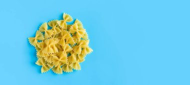 Mavi arka planda fotokopi alanı olan çiğ makarna. İtalyan mutfak malzemesi afişinin en üst görüntüsü.