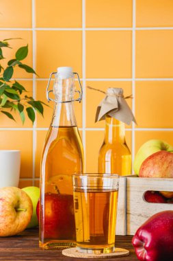 Ahşap bir masada şişedeki elma suyu. Elmalar sandıkta. Taze meyvelerin yan görünümü.