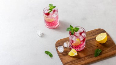 Ahşap kesme tahtasındaki buzlu ahududu kokteyli. Nane ve limonlu ferahlatıcı bir meyve suyu..