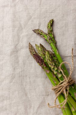 Fotokopi alanı olan keten masa örtüsü üzerinde yeşil kuşkonmaz. Taze ve doğal pişmemiş kuşkonmaz. Sağlıklı bitki yiyeceği.