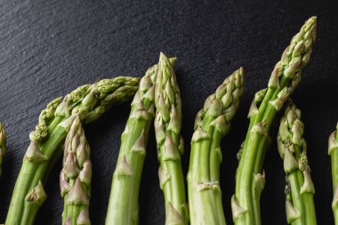Siyah arka planda yeşil kuşkonmaz. Taze ve doğal pişmemiş kuşkonmaz. Yakın çekim. Sağlıklı bitkiler..