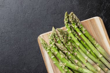 Siyah arka planda yeşil kuşkonmaz. Taze ve doğal pişmemiş kuşkonmaz. Sağlıklı bitki yiyeceği.