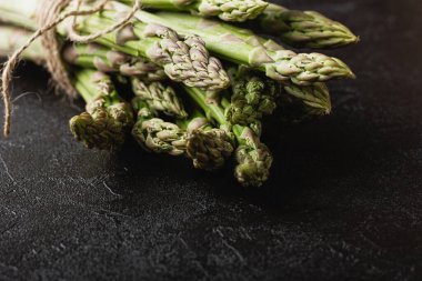 Siyah arka planda yeşil kuşkonmaz. Taze ve doğal pişmemiş kuşkonmaz. Yakın çekim. Sağlıklı bitkiler..