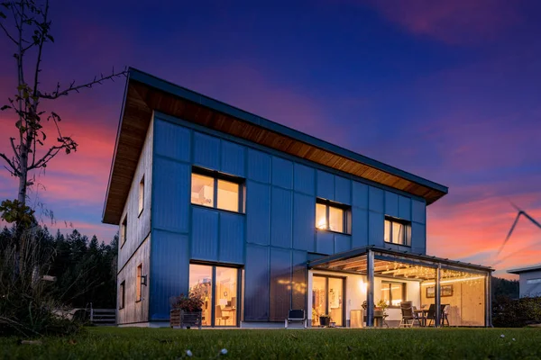 太陽光や太陽熱コレクターと持続可能で自給自足のエネルギー概念を持つ夜の照明付きの木造プレハブ住宅 — ストック写真